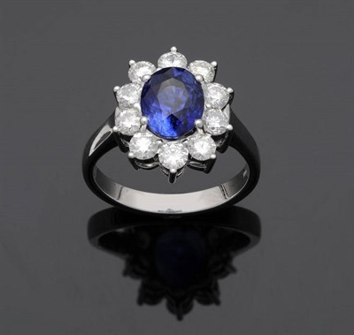 Lot 552 - A Sapphire and Diamond Cluster Ring, the oval mixed cut sapphire in a white four claw setting...