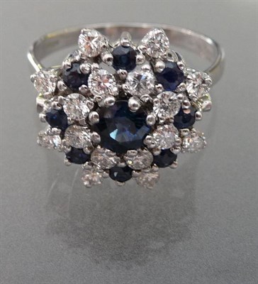 Lot 563 - An 18 Carat White Gold Sapphire and Diamond Cluster Ring, three tiers of round brilliant cut...