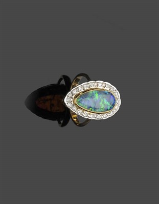 Lot 594 - A Black Opal and Diamond Cluster Ring, the pear shaped cabochon black opal in a yellow rubover...