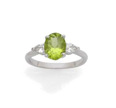 Lot 617 - A Peridot and Diamond Three Stone Ring, the oval cut peridot flanked by a pear cut diamond to...