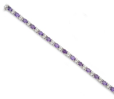 Lot 618 - An Amethyst and Diamond Line Bracelet, the oval cut amethysts spaced by pairs of round...