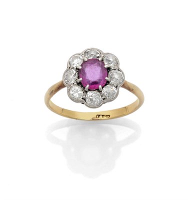 Lot 622 - A Ruby and Diamond Cluster Ring, the oval mixed cut ruby in a white claw setting within a border of