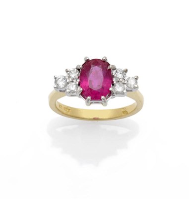 Lot 624 - An 18 Carat Gold Ruby and Diamond Ring, the oval mixed cut ruby sits between a cluster of three...