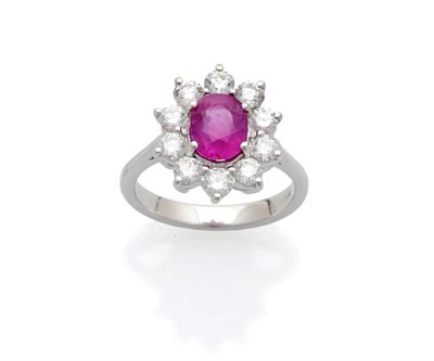 Lot 630 - A Ruby and Diamond Cluster Ring, the oval mixed cut ruby within a border of round brilliant cut...