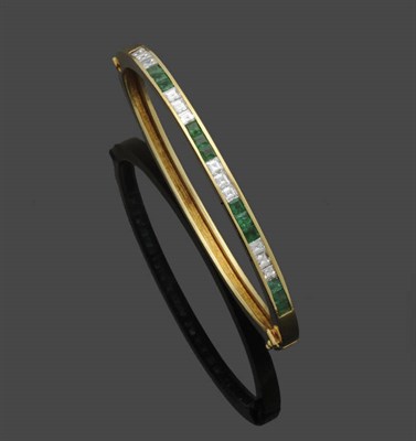 Lot 641 - An Emerald and Diamond Bangle, alternating series of three step cut emeralds and three step cut...