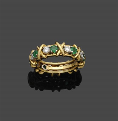 Lot 645 - An 18 Carat Gold Emerald and Diamond Full Eternity Ring, by Tiffany, pairs of round brilliant...