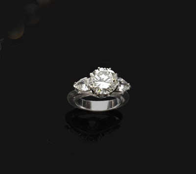 Lot 672 - A Diamond Three Stone Ring, the round brilliant cut diamond flanked by a pear cut diamond on...