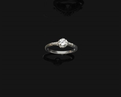 Lot 673 - A Platinum Diamond Ring, a round brilliant cut diamond is flanked by a tapered baguette cut diamond