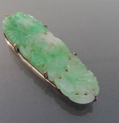 Lot 677 - A Jade Clip, a carved oval jade panel set on an engraved white metal clip, measures 4.4cm by 1.3cm.