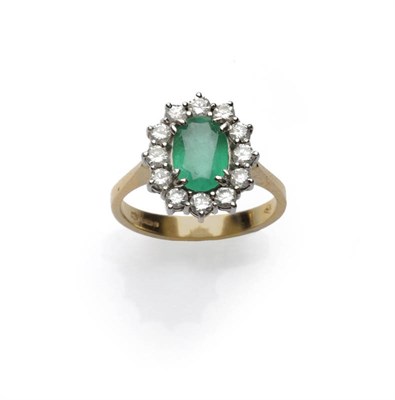 Lot 685 - An 18 Carat Gold Emerald and Diamond Cluster Ring, the oval mixed cut emerald within a border...