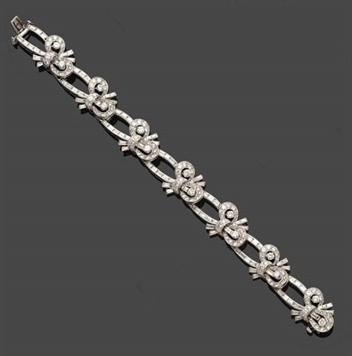 Lot 699 - A Diamond Bracelet, round brilliant and baguette cut diamonds in the form of bows are linked by...