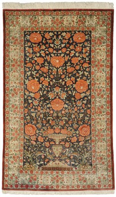 Lot 1343 - A Ghom Silk Rug Central Persia The indigo field with an urn issuing flowers enclosed by ivory...