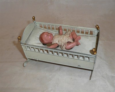 Lot 102 - A Celluloid Baby in Tinplate Cot Toy, the white tinplate cot with weighted celluloid wriggling...