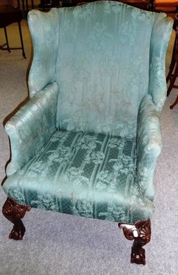 Lot 1544 - A Mahogany Framed Wing Back Armchair, late 19th century, upholstered in green floral print...