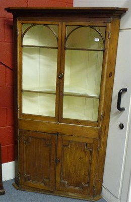 Lot 1556 - A George III Pine Corner Cabinet, the bold cornice above two glazed doors enclosing a white painted