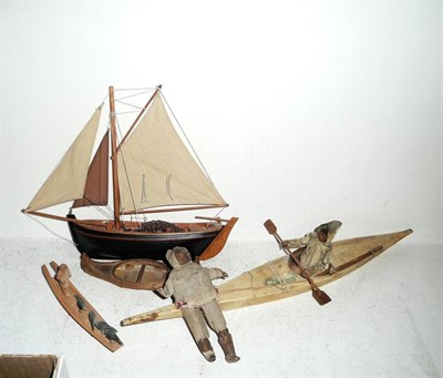 Lot 163 - Wooden Toys, including an Inuit in a hide covered canoe, another Inuit figure and a fishing boat.