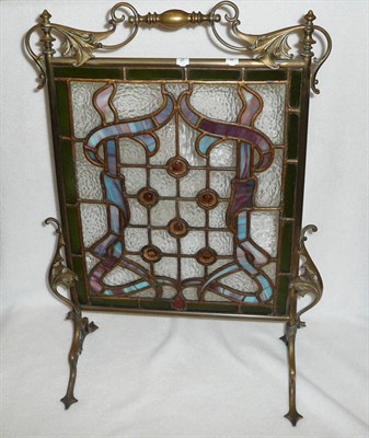 Lot 1621 - An Art Nouveau Brass and Leaded Glass Firescreen, with ornate scrolling handle, coloured glass...