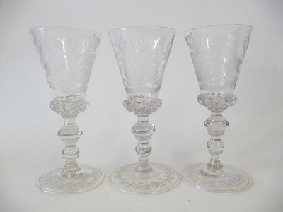 Lot 13 - A Set of Three Light Baluster Wine Glasses, circa 1900, each trumpet bowl engraved with an armorial