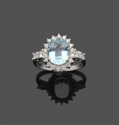 Lot 495 - An Aquamarine and Diamond Cluster Ring, the oval mixed cut aquamarine sits within a border of round