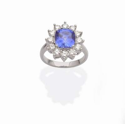 Lot 505 - A Sapphire and Diamond Cluster Ring, the cushion cut sapphire within a border of round...