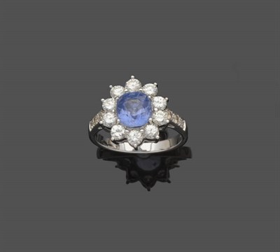 Lot 527 - A Sapphire and Diamond Cluster Ring, the pale blue cushion cut sapphire within a border of...