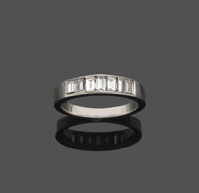 Lot 545 - A Diamond Half Eternity Ring, seven graduated baguette cut diamonds in a channel setting, on a...