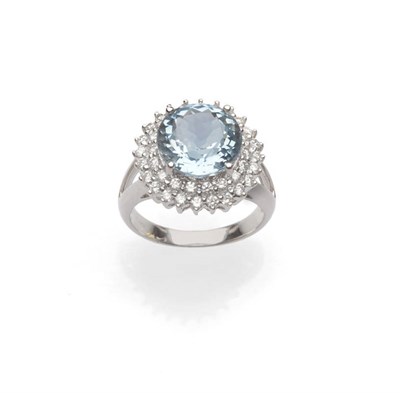 Lot 556 - An Aquamarine and Diamond Cluster Ring, the round brilliant cut aquamarine within a double...