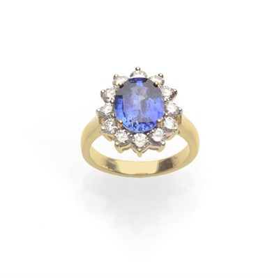 Lot 557 - A Sapphire and Diamond Cluster Ring, the oval mixed cut sapphire within a border of round brilliant