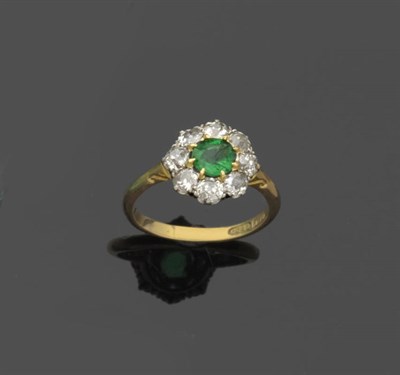 Lot 578 - An Emerald and Diamond Cluster Ring, a round brilliant cut emerald within a border of old cut...