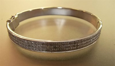 Lot 582 - An 18 Carat White Gold Diamond Bangle, the hinged bangle set with three rows of round brilliant cut