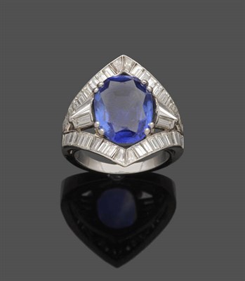 Lot 607 - A Sapphire and Diamond Ring, an oval mixed cut sapphire in a white claw setting sits within a frame