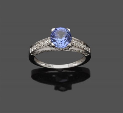 Lot 614 - A Sapphire and Diamond Ring, the round mixed cut sapphire in a diamond encrusted setting on a plain