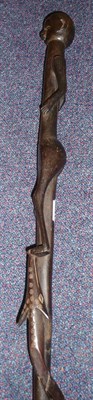 Lot 190 - A Zulu Ebony Staff, carved as a man standing with one foot resting on the mouth of a snake with...