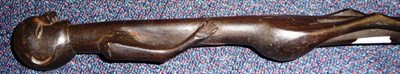 Lot 263 - A Zulu Ebony Staff, carved as a man standing with one foot resting on the mouth of a snake with...