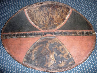 Lot 303 - An Early Masai Buffalo Hide Shield, of traditional oval form, the hide decorated with geometric...