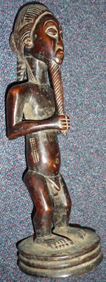 Lot 196 - A Baule, Congo Wood Figure of a Man, standing on a circular plinth, his hands tugging on his...