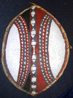 Lot 283 - A Masai Painted Hide Shield, of convex elliptical form, painted with a central band of lozenge...