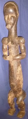 Lot 310 - A Fang Dark Wood Ancestor Type Figure, as a woman standing on bent legs, holding a sceptre...