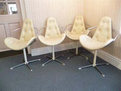 Lot 1264 - A Set of Four Cream Vinyl and Chrome Swivel Arm Chairs, with button seats and backs, shaped arm...