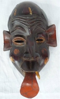 Lot 343 - A Bamileke Painted Wood Mask, with carved furrowed forehead, pierced elliptical eyes, large red...