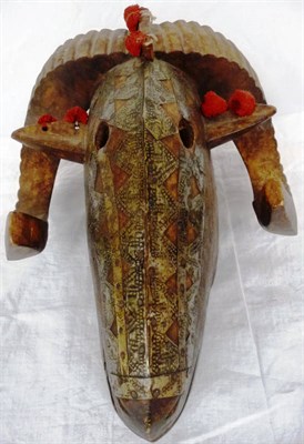 Lot 345 - A Baule Ram Mask, with downcurved and fluted horns, the skull with medial ridge set with red cotton