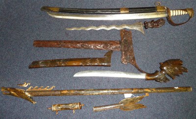 Lot 328 - A Malayan Kris, with wavy damascened blade, hardwood grip and scabbard carved with masks and...