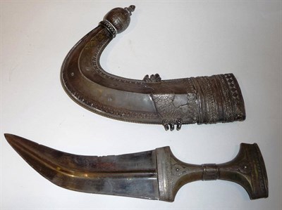 Lot 337 - An Arab Jambiya, the curved steel blade with medial ridge, the waisted silver coloured metal...