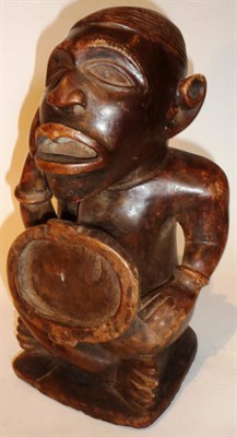 Lot 355 - A Yombe Nkisi Power Figure, Congo, seated cross legged, with one hand raised to his cheek, his...