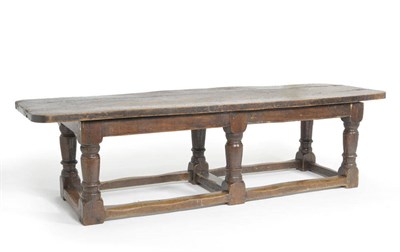 Lot 1435 - An Elm and Oak Refectory Table, the rounded three-plank top above a plain frieze, raised on six...