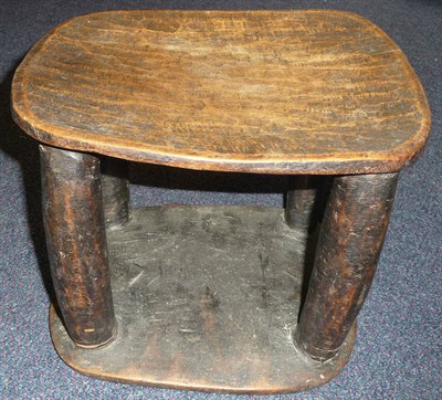 Lot 327 - An East African Wooden Stool, the dished rounded rectangular seat with lightly adzed decoration, on