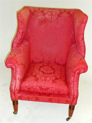 Lot 1480 - A Wing Back Armchair, probably Regency, upholstered in red floral silk damask, the padded back...