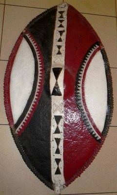 Lot 343 - A Kikuyu Hide Dance Shield, of elliptical form, painted with curved panels and chevron bands in...