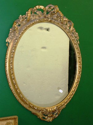 Lot 1565 - A Gilt Composition Mirror, early 19th century, the oval plate contained within a moulded frame, the