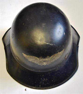 Lot 203 - A German Third Reich Luftschutz Helmet, the dark blue skull with silvered transfer badge, the broad